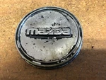 Mazda: 1/8 Inch Center Cap, Metal, & Chrome, 1992, 1993, 1994 2012, # 1-1-T4. Fixed Price $14.00.